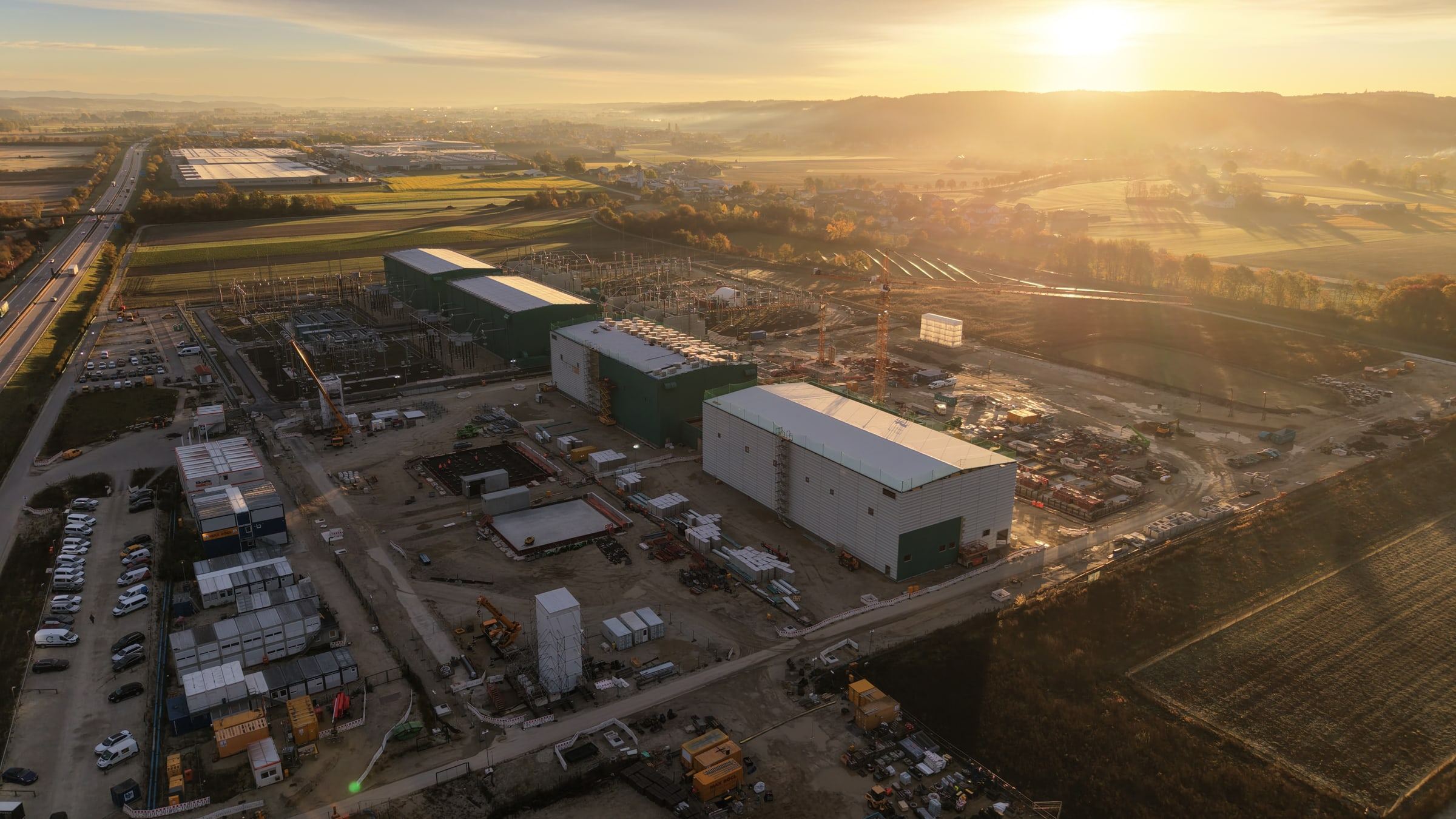 Aerial view of the HVDC construction site at sunrise, with large halls and site facilities