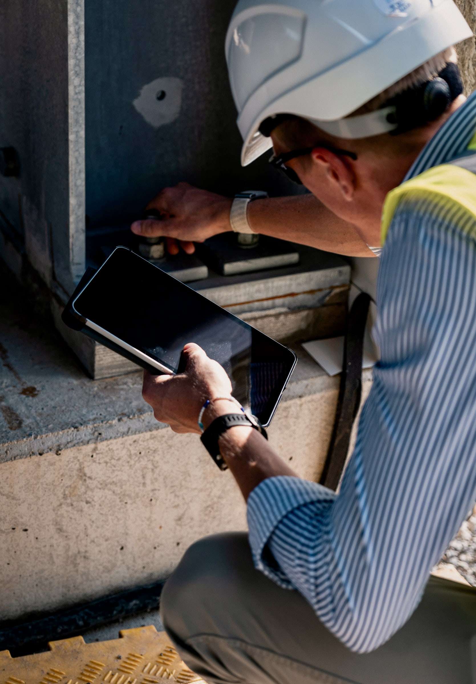 Andreas Postler in a helmet checking documents on a tablet on site